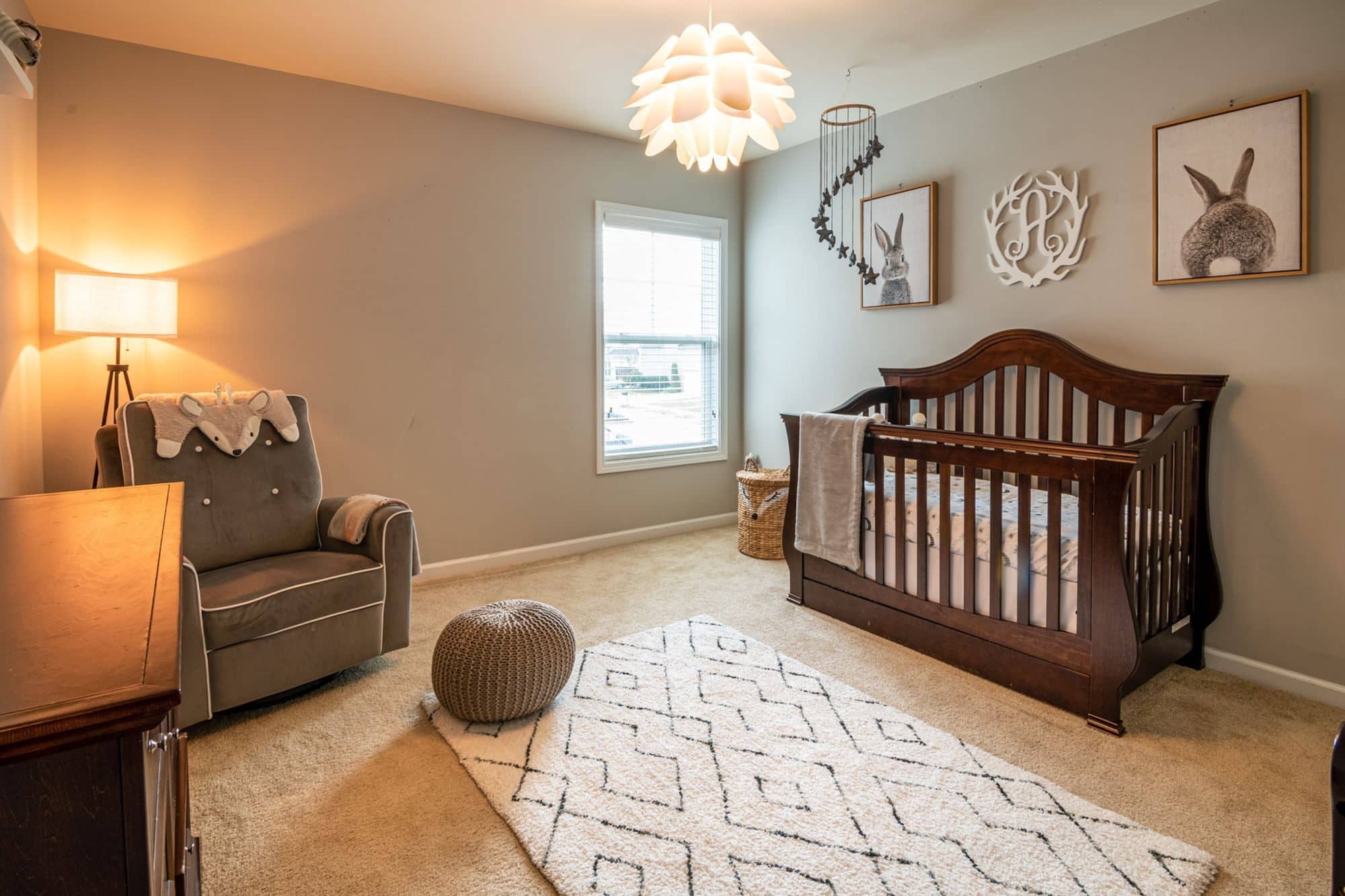 A baby's nursery with a wooden crib, a rocking chair and a patterned rug