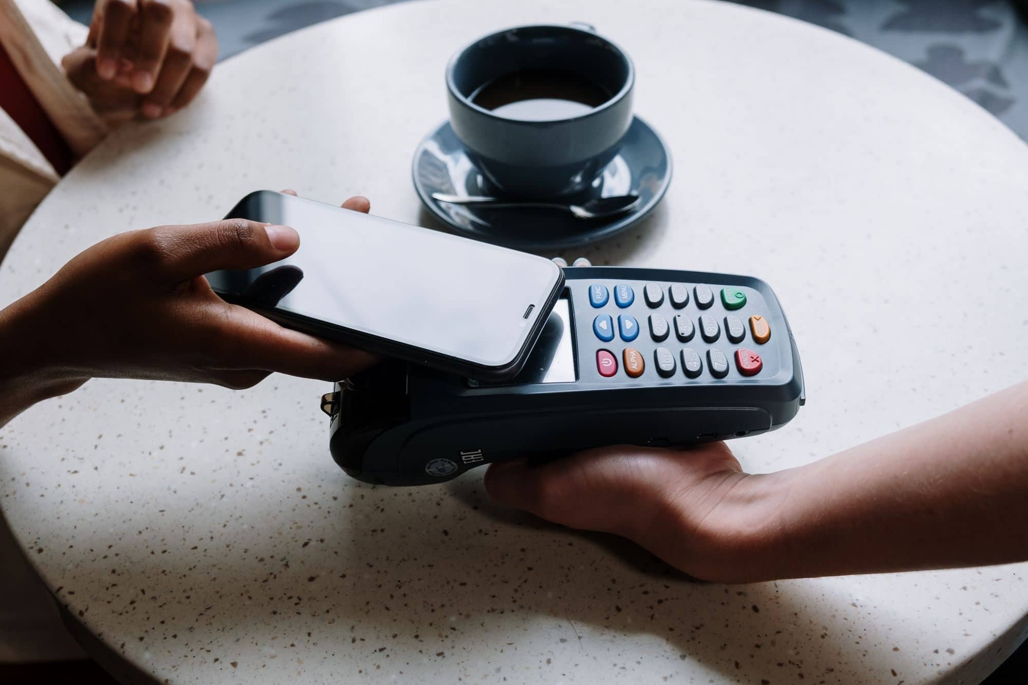 A customer taps a smartphone on a card reader to pay