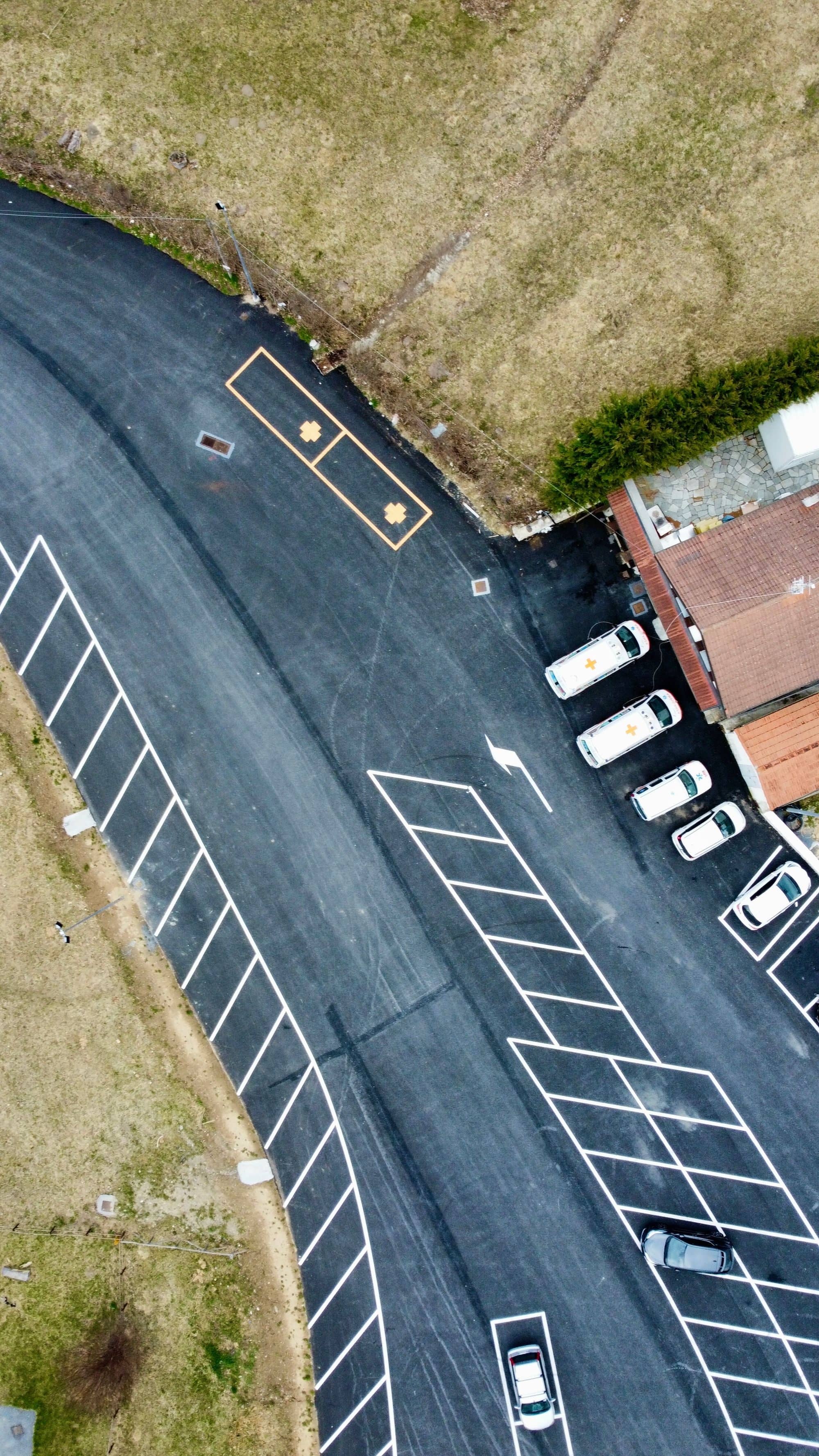 Aerial view of a curving road and a freshly striped parking lot